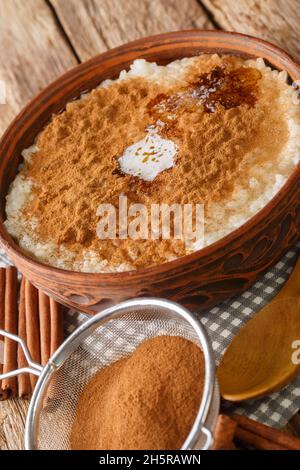 Risengrod ou Risgrynsgrot de bouillie de riz, avec du sucre, du beurre et de la cannelle, dans le bol de la table.Verticale Banque D'Images
