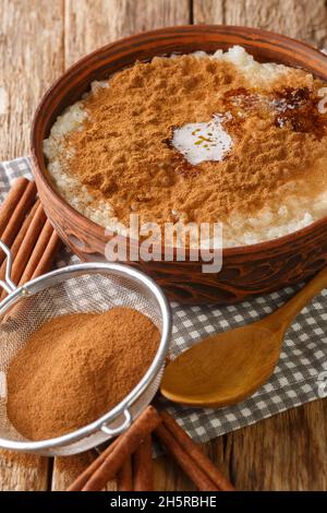 Pudding danois de riz également connu sous le nom de Risengrod avec du sucre, du beurre et de la cannelle dans le bol sur la table.Verticale Banque D'Images