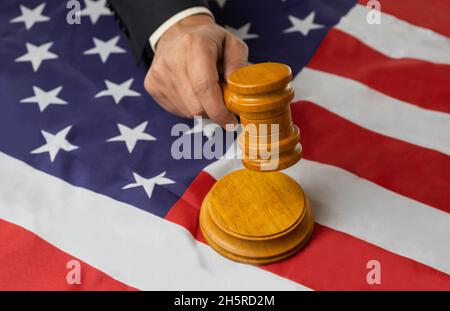 Homme juge main tenant le gavel en bois de frapper sur bloc de sondage sur le drapeau des états-unis fond.Justice concept avec le drapeau des états-unis d'amérique Banque D'Images