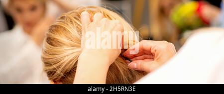 Mains de styliste de cheveux faisant la coiffure professionnelle des cheveux longs de femme dans un salon de beauté Banque D'Images