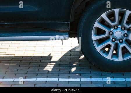 Le vus se fragmente avec la roue arrière, l'ombre de la voiture sur la chaussée par une journée ensoleillée, gros plan Banque D'Images