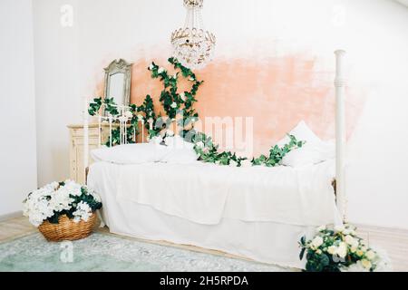 Intérieur d'une chambre blanche et lumineuse avec des fleurs décoratives sur un mur. Banque D'Images