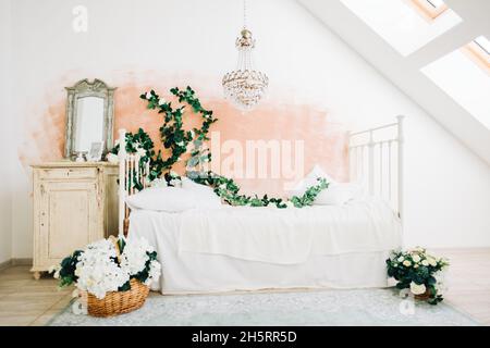 Intérieur d'une chambre blanche et lumineuse avec des fleurs décoratives sur un mur. Banque D'Images