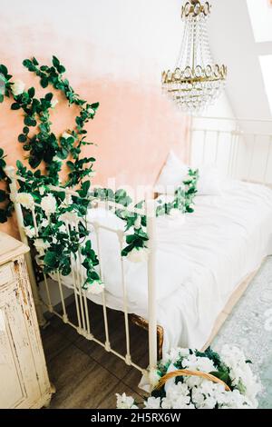 Intérieur d'une chambre blanche et lumineuse avec des fleurs décoratives sur un mur. Banque D'Images