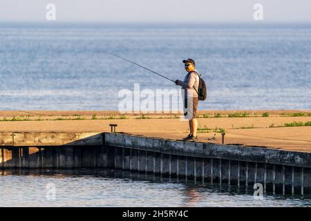 Un seul homme pêchant le long de la jetée au lever du soleil dans un parc local près d'Egg Harbor dans le comté de Door, Wisconsin. Banque D'Images