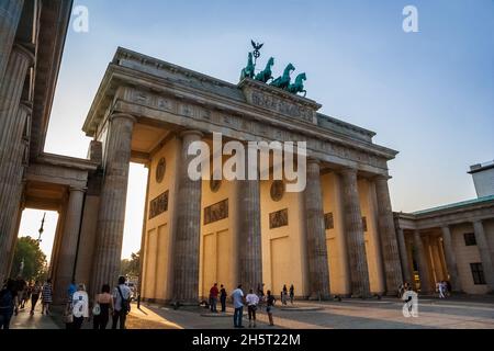 Belle vue sur les personnes se trouvant en face du monument le plus célèbre de Berlin, la porte de Brandebourg (Brandenburger Tor) dans la soirée et... Banque D'Images