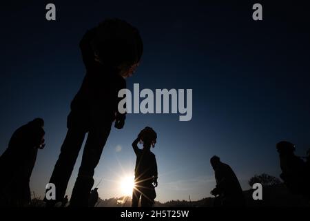 Katmandou, Népal.11 novembre 2021.Les adeptes de la silhouette se déplacent vers leurs maisons tout en portant des offrandes après avoir conclu le festival Chhath sur la rive du Saint fleuve Bagmati.dans un ancien festival hindou, des rituels sont exécutés pour remercier le Dieu du soleil pour avoir soutenu la vie sur terre.Chhath Puja est un festival hindou où les dévots prient dieu et offrent Prasad et des spécialités spéciales au coucher du soleil et avant le lever du soleil et de terminer leur jeûne en mangeant 'Prasad' et des spécialités spéciales.Crédit : SOPA Images Limited/Alamy Live News Banque D'Images