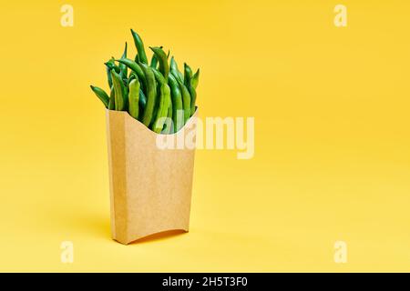 Grains de café verts frais dans une boîte de papier pour aliments rapides sur fond jaune vif avec espace de copie.Concept de saine alimentation Banque D'Images