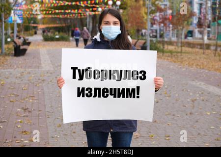 Une femme masquée possède une affiche avec du texte en russe, traduit du russe - la tuberculose est curable Banque D'Images