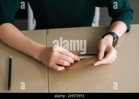 Vue rapprochée du dessus d'une jeune femme méconnue tenant dans l'enveloppe des mains avec la lettre reçue assise à une table. Banque D'Images