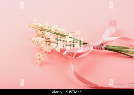 Bouquet de nénuphars noué avec un ruban rose sur fond rose.Concept de ressort délicat Banque D'Images