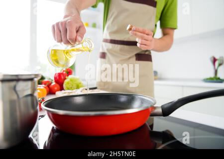 Vue rognée portrait d'un type attrayant cuisant dîner domestique verser huile friture ingrédient à la maison cuisine à l'intérieur Banque D'Images