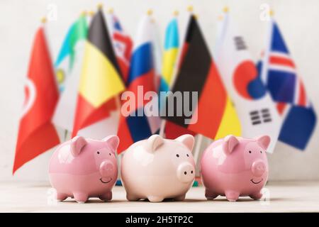 Trois banques de cochon sur le fond des drapeaux de différents pays, le concept sur le thème du budget Banque D'Images