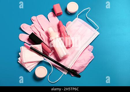 ensemble de sacs cosmétiques de voyage de protection pour femmes.Masque rose, gants, assainisseur, gel pour les lèvres, crayon et rouge à lèvres sur fond bleu. Banque D'Images