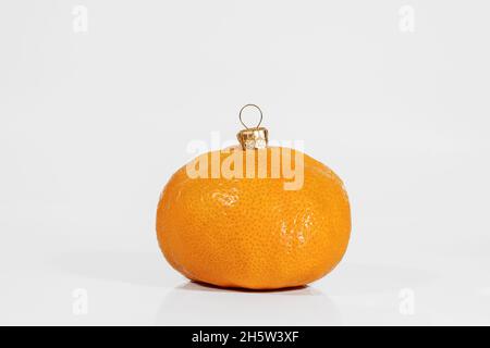 Mandarine comme boule de Noël isolée sur blanc avec ombre et réflexion.Jouet arbre de Noël.Concept de Noël ou de nouvel an. Banque D'Images