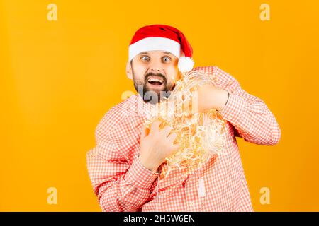 Un homme dans un chapeau de Père Noël tient une guirlande entre ses mains Banque D'Images