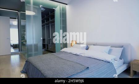 Nouvelle chambre d'hôtel avec une chambre pleine de lumière du soleil.Vidéo.Bel intérieur avec un lit double, une lampe, une table de chevet et un dressing Banque D'Images
