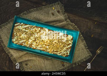 Gâteau avec chocolat blanc, noix, amandes et pistaches comme garniture sur fond de bois, vue du dessus. Banque D'Images