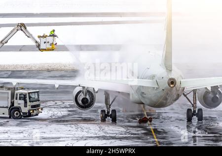 L'équipe au sol assure le dégivrage. Ils pulvérisent l'avion, ce qui empêche la formation de givre Banque D'Images