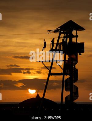 Voyage sur l'attraction Zip Wire, Brighton, Angleterre.Palace Pier et coucher de soleil au-delà. Banque D'Images