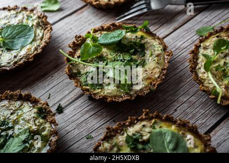 Du dessus des gâteaux de chou-fleur et de noix avec des légumes verts près de la fourchette sur une table en bois plantée Banque D'Images