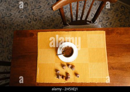 Vue de dessus d'une tasse en céramique d'espresso fraîchement préparé sur la soucoupe placée sur une serviette près des acorns sur une table en bois Banque D'Images