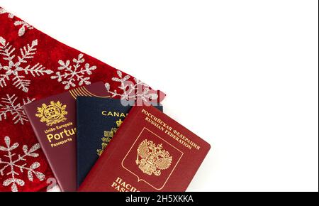 Trois passeports différents isolés sur blanc avec décoration de Noël.Passeports canadiens, portugais et russes pour entrée dans différents pays.CL Banque D'Images