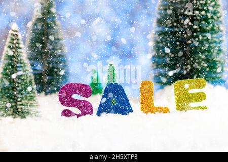 Soldes d'hiver.L'inscription VENTE dans la neige sur fond de sapins verts dans la neige Banque D'Images