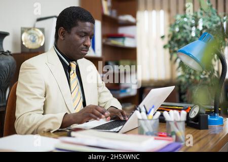 Homme d'affaires afro-américain concentré travaillant avec un ordinateur portable Banque D'Images
