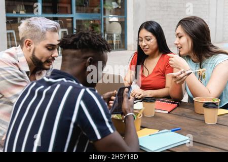 Divers amis qui s'amusent à manger à emporter la nourriture en plein air - des gens multiraciaux utilisant les tendances technologiques - Focus sur les filles asiatiques Banque D'Images