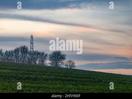 Dans de belles terres arables, doucement vallonnées, dépassant d'un épais d'arbres au loin, faisant passer des câbles à travers les terres agricoles du sud de l'Angleterre, en couches Banque D'Images