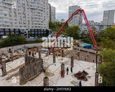 Alimenter le mélange de travail de béton sur le chantier avec une pompe à béton pour verser la fondation. Banque D'Images