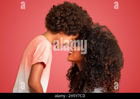 Portrait d'une jeune mère afro-américaine avec un tout-petit fils.Arrière-plan rouge.Famille brésilienne. Banque D'Images