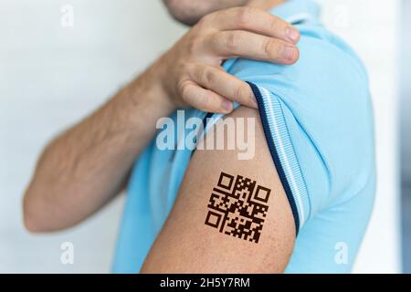 L'homme montre son épaule avec un code qr, une confirmation de la vaccination contre le coronavirus Covid 19.Tatouage temporaire. Banque D'Images