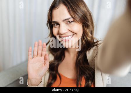 Belle jeune latine visage souriant femme tenant un appareil photo ou un téléphone à la main et elle fait un appel vidéo ou elle enregistre de la vidéo pour ses fans, appel vidéo a Banque D'Images