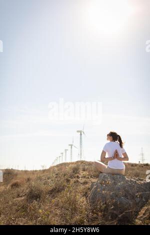 La fille est assise sur une pierre contre le fond des éoliennes.Vue arrière. Banque D'Images