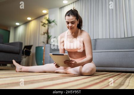 Jeune femme latine attrayante faisant yoga stretching yoga en ligne à la maison. Banque D'Images