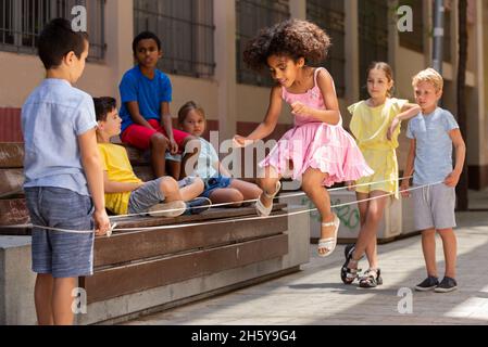 Jeu de saut de petite fille péruvienne par le groupe de caoutchouc avec des amis européens Banque D'Images