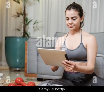 Jeune femme latine attrayante s'exerçant en ligne à la maison. Banque D'Images