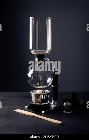 Machine à café sous vide également connue sous le nom de cafetière aspirateur, siphon ou syphon sur table rustique en pierre noire. Banque D'Images