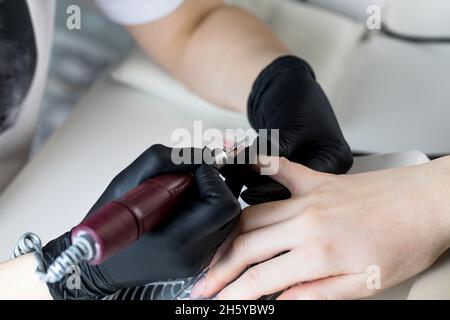 Un manucuriste enlève le gel vernis des ongles à l'aide d'une fraise.Gros plan sur la manucure de quincaillerie.Revêtement de la gomme laque sur les ongles Banque D'Images