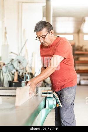 Homme adulte travaillant manuellement avec une machine de rabotage du bois Banque D'Images
