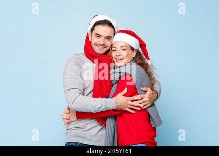 Portrait d'un couple caucasien heureux en tenues de Noël se tenant les uns les autres sur fond bleu clair isolé de studio Banque D'Images