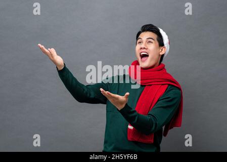 Portrait studio d'un homme asiatique surpris portant une tenue de noël avec ses bras levés Banque D'Images