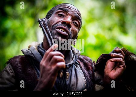 Septembre 2017.Le guide Batwa, Machate Emanuel, dirige la visite du sentier forestier communautaire de Buniga dans sa langue locale, les Pygmées de Batwa ont été expulsées de leurs terres d'origine dans la forêt au début des années 1990, lorsque les parcs nationaux ont été établis,les laisser sans terre et pauvres dans une société qui les considérait comme une classe inférieure.Aujourd'hui, certains d'entre eux essaient de faire la rencontre des extrémités en organisant des promenades sur les sentiers; des visites culturelles qui incluent des exemples de l'endroit et de la façon dont ils utilisent pour vivre dans la forêt, ainsi que du chant, de la danse et de l'artisanat pour la vente.Nkuringo, Ouganda. Banque D'Images