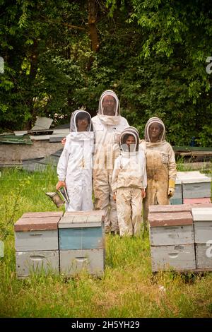 Une famille de apiculture portant des vêtements de protection près de leurs ruches ca.8 juin 2017 Banque D'Images