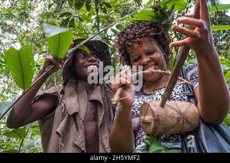 Septembre 2017.Les Pygmées Batwa ont été expulsées de leurs terres d'origine dans la forêt au début des années 1990, lorsque les parcs nationaux ont été établis, les laissant sans terre et pauvres dans une société qui les considérait comme une classe inférieure.Aujourd'hui, certains d'entre eux essaient de faire la rencontre des extrémités en organisant des promenades sur les sentiers; des visites culturelles qui incluent des exemples de l'endroit et de la façon dont ils utilisent pour vivre dans la forêt, ainsi que du chant, de la danse et de l'artisanat pour la vente.Buhoma, Ouganda. Banque D'Images