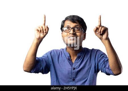 Un jeune Indien en robe bleue pointant vers le haut avec les deux pointeurs sur fond blanc Banque D'Images