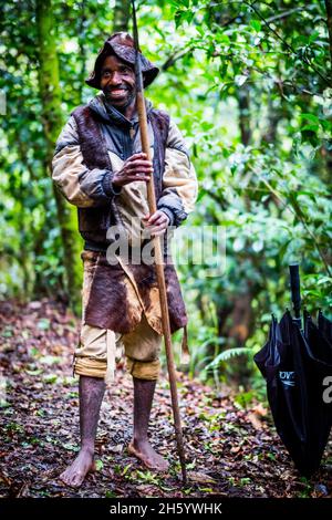 Septembre 2017.Le guide Batwa, Machate Emanuel, dirige la visite du sentier forestier communautaire de Buniga dans sa langue locale, les Pygmées de Batwa ont été expulsées de leurs terres d'origine dans la forêt au début des années 1990, lorsque les parcs nationaux ont été établis,les laisser sans terre et pauvres dans une société qui les considérait comme une classe inférieure.Aujourd'hui, certains d'entre eux essaient de faire la rencontre des extrémités en organisant des promenades sur les sentiers; des visites culturelles qui incluent des exemples de l'endroit et de la façon dont ils utilisent pour vivre dans la forêt, ainsi que du chant, de la danse et de l'artisanat pour la vente.Nkuringo, Ouganda. Banque D'Images