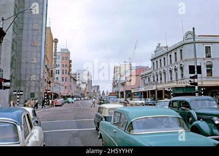 Centre-ville de Port Elizabeth, Afrique du Sud – une vue à Kolnicks Corner en 1962.Cette vue sur la rue main (maintenant l'avenue Govan Mbeki) en direction de l'hôtel de ville a été prise à sa jonction avec la rue Russell.Aujourd'hui, un énorme survol d'autoroute traverse la jonction.Certains des bâtiments de gauche survivent encore, mais le côté droit de la rue a été complètement remanié.Cette image provient d'une ancienne transparence couleur 35 mm amateur, une photographie vintage des années 1960. Banque D'Images